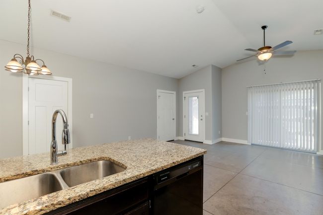 Kitchen featuring pendant lighting, sink, black dishwasher, light stone countertops, and vaulted ceiling | Image 10