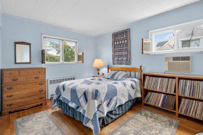 Bedroom with radiator, hardwood / wood-style floors, crown molding, and an AC wall unit | Image 11