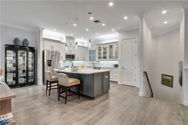 Featuring stainless steel appliances, 3 pendant light fixtures, quartz counters, and an island with cabinets below for storage | Image 6