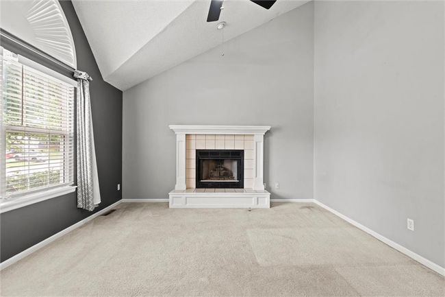 Unfurnished living room with lofted ceiling, a ceiling fan, carpet floors, and a fireplace | Image 5