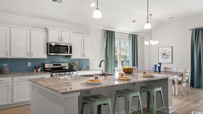 Kitchen featuring stainless steel appliances, a sink, vaulted ceiling, tasteful backsplash, and white cabinetry | Image 4