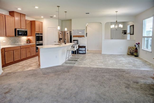 Kitchen with stainless steel appliances, a chandelier, decorative backsplash, brown cabinets, and recessed lighting | Image 18