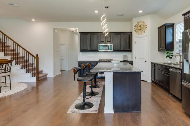 Kitchen featuring appliances with stainless steel finishes, a sink, a breakfast bar area, a kitchen island, and light stone counters | Image 10