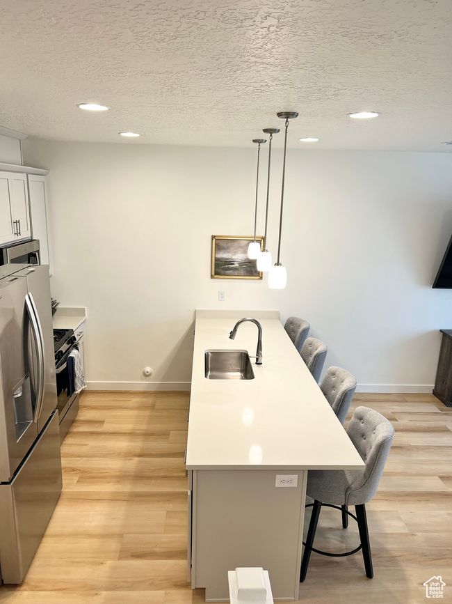 Kitchen with appliances with stainless steel finishes, a kitchen breakfast bar, a textured ceiling, recessed lighting, and decorative light fixtures | Image 5