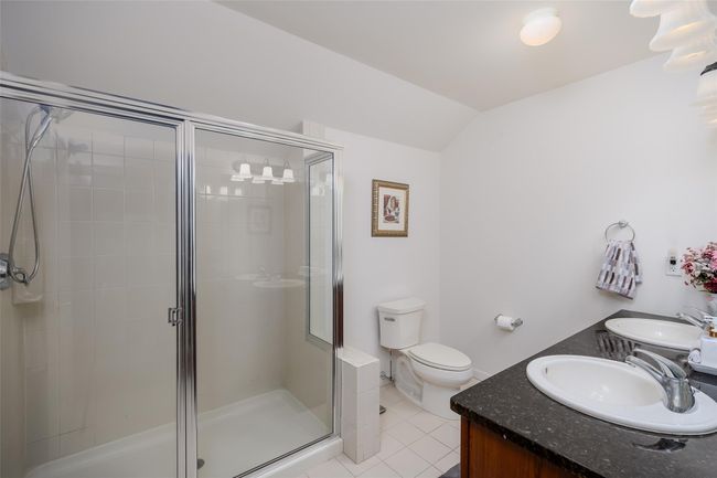 Full bath featuring a shower stall, double vanity, tile patterned flooring, and lofted ceiling | Image 23