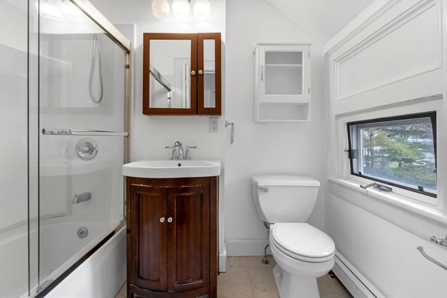 Bathroom featuring toilet, baseboards, baseboard heating, vanity, and bath / shower combo with glass door | Image 37