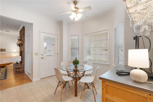 Dining space featuring ornamental molding, a ceiling fan, light tile patterned flooring, and a brick fireplace | Image 23