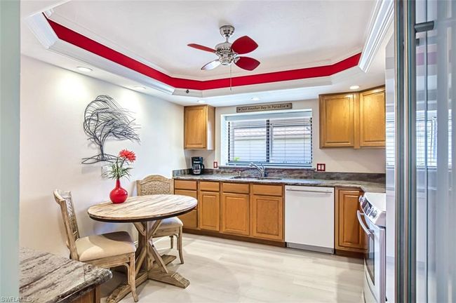 Kitchen featuring white appliances, ornamental molding, a sink, a ceiling fan, and a tray ceiling | Image 21