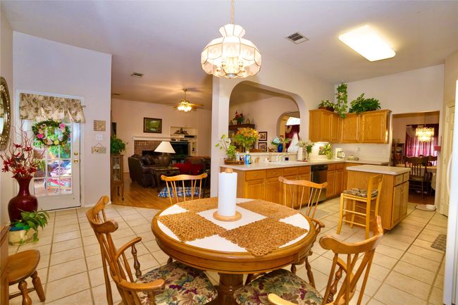 Dining room with light tile patterned floors, arched walkways, ceiling fan, a chandelier, and a fireplace | Image 16