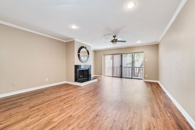 Unfurnished living room with light wood-style flooring, baseboards, crown molding, and ceiling fan | Image 9
