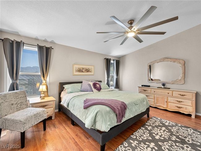 Bedroom featuring a ceiling fan, lofted ceiling, light wood-style floors, and a textured ceiling | Image 29