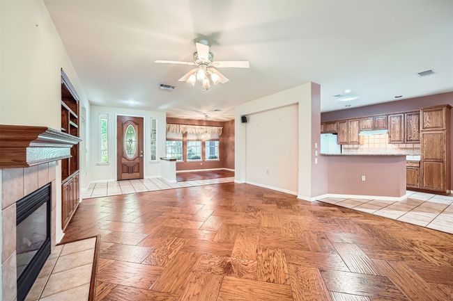 Unfurnished living room with a tile fireplace, ceiling fan, and baseboards | Image 7