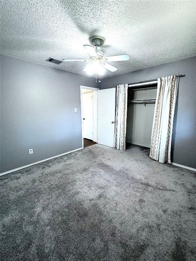 Unfurnished bedroom with a textured ceiling, carpet floors, a closet, and a ceiling fan | Image 21