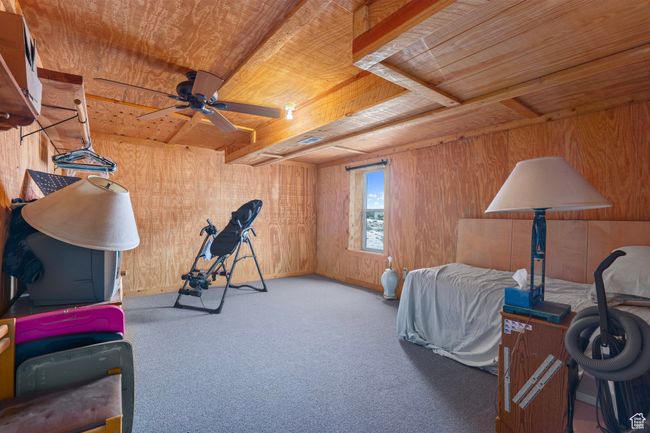Carpeted bedroom with ceiling fan, wood walls, and wooden ceiling | Image 10