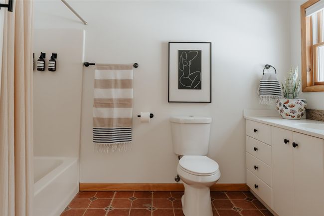 Full bathroom with tile patterned floors, vanity, toilet, and shower / bath combo with shower curtain | Image 13
