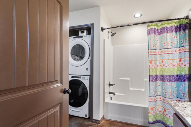 Washroom with stacked washer / drying machine and laundry area will stay with property | Image 8