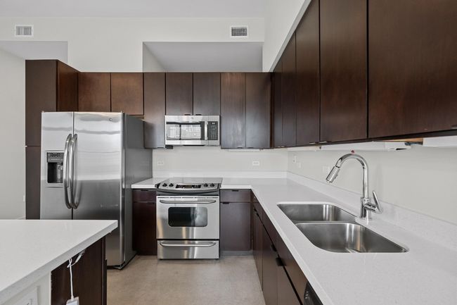 Kitchen with a sink, light countertops, dark brown cabinetry, and stainless steel appliances | Image 5