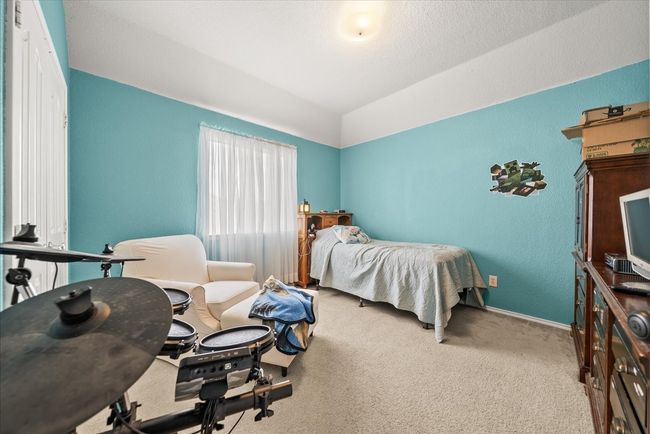 Carpeted bedroom with lofted ceiling, a textured wall, and baseboards | Image 35