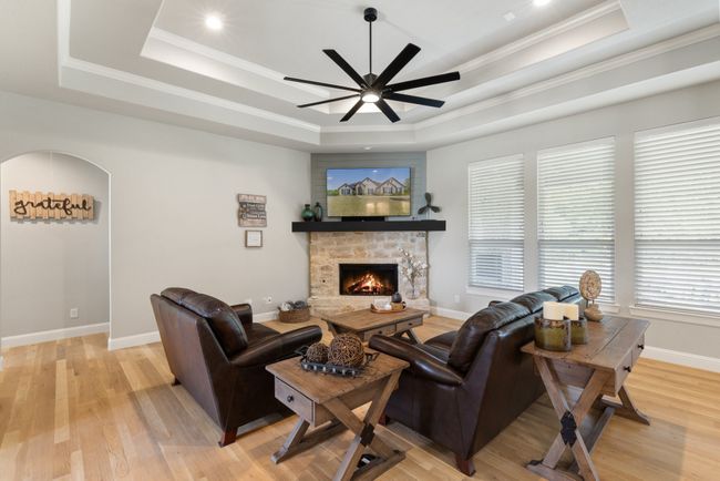 Living area featuring light wood-style floors, ceiling fan, crown molding, a fireplace, and a raised ceiling | Image 8