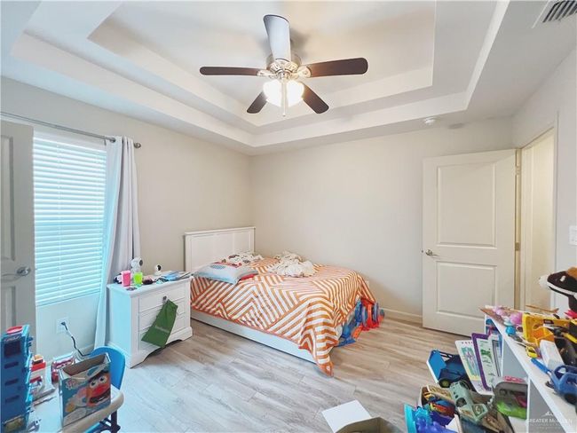 Bedroom featuring a raised ceiling, light wood-type flooring, and a ceiling fan | Image 6