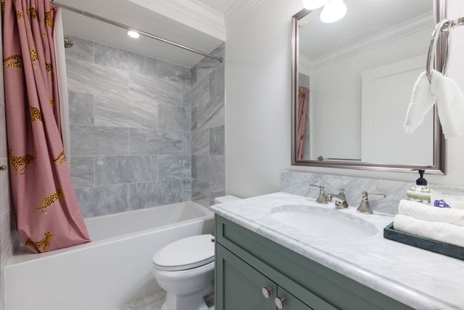 Bathroom with shower / tub combo, vanity, ornamental molding, and toilet | Image 17