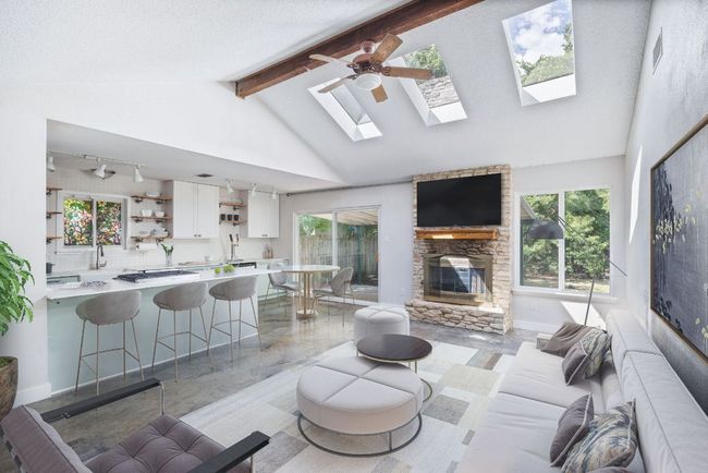 Living area with healthy amount of natural light, a skylight, a fireplace, beamed ceiling, and high vaulted ceiling | Image 4
