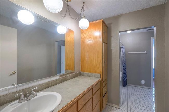 Full bath with a shower with shower curtain, vanity, a textured ceiling, tile patterned flooring, and baseboards | Image 28