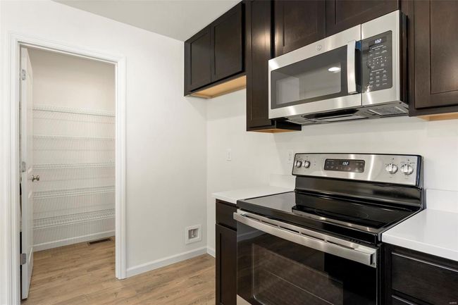 Kitchen with dark brown cabinets, light hardwood / wood-style floors, and stainless steel appliances | Image 13