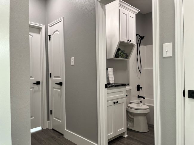 Full bath featuring wood finished floors, washtub / shower combination, and a textured wall | Image 11