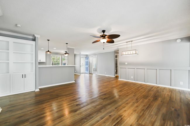 Unfurnished living room featuring ceiling fan, dark wood-style flooring, and ornamental molding | Image 15