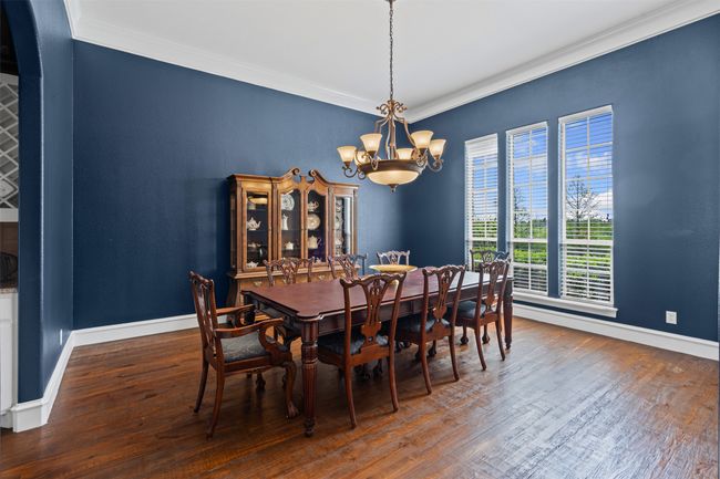 Dining area with crown molding, wood finished floors, a notable chandelier, and baseboards | Image 16