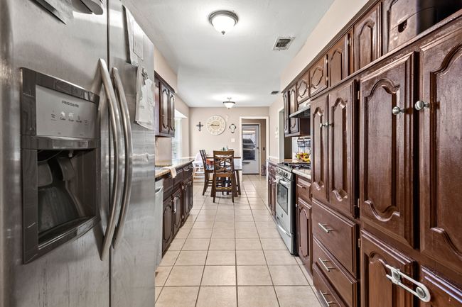 Kitchen featuring appliances with stainless steel finishes, light tile patterned floors, and dark brown cabinetry | Image 5