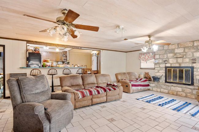 Living room featuring a fireplace, a ceiling fan, and crown molding | Image 9