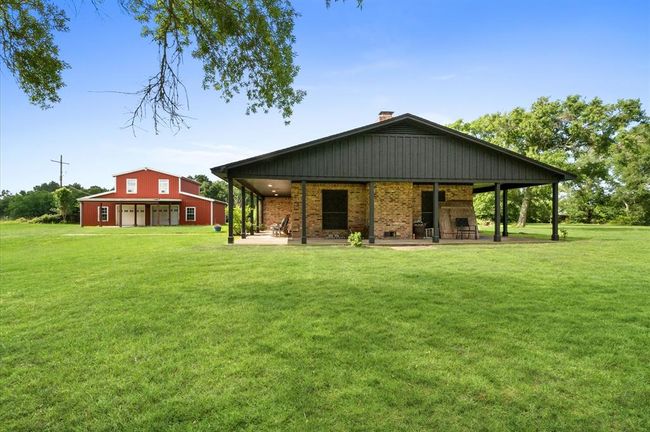 Another great view of the wrap around porch and barn with efficiency living space. | Image 25