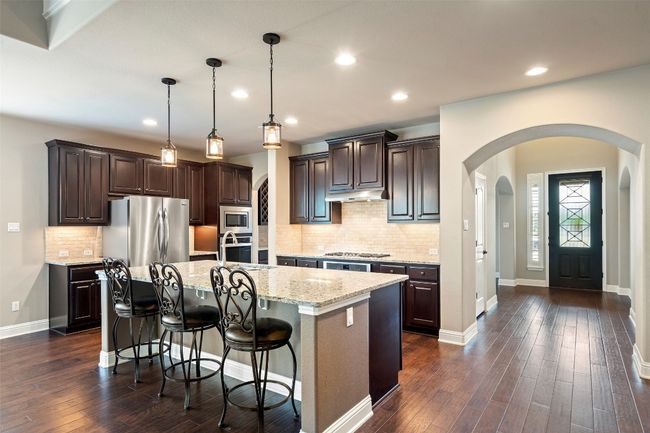 Kitchen featuring arched walkways, stainless steel appliances, dark brown cabinets, dark wood-style floors, and recessed lighting | Image 7