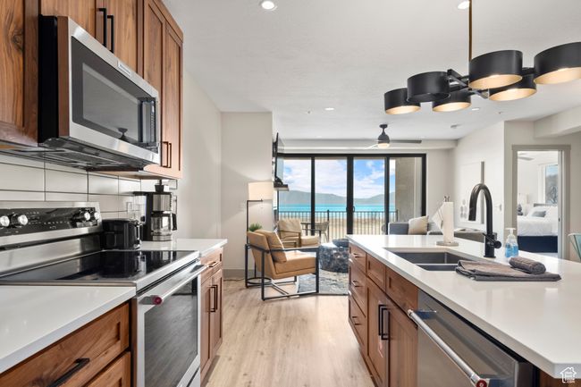 Kitchen featuring appliances with stainless steel finishes, a sink, open floor plan, brown cabinets, and light wood-style flooring | Image 44