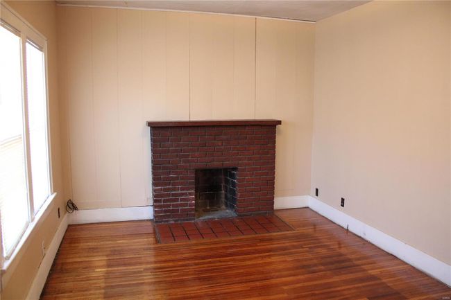 Unfurnished living room featuring a brick fireplace, plenty of natural light, baseboards, and wood finished floors | Image 5