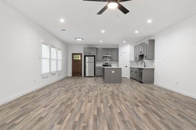 Kitchen featuring gray cabinets, stainless steel appliances, wood-type flooring, and a kitchen island | Image 2