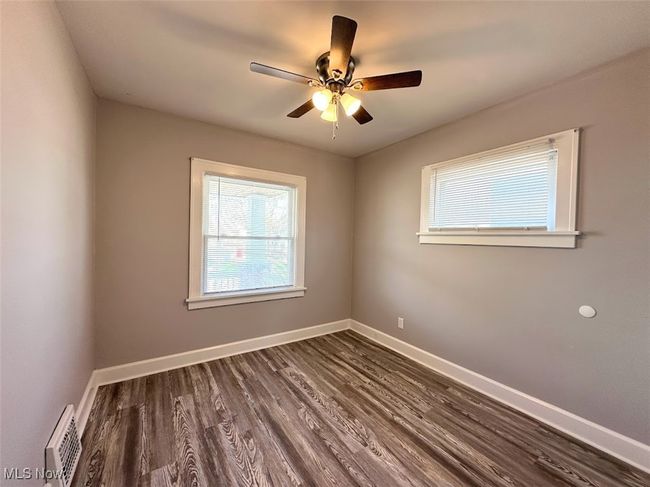 Unfurnished room with a wealth of natural light, visible vents, dark wood-style floors, and baseboards | Image 7