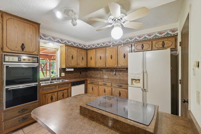 Kitchen featuring white appliances, a sink, brown cabinetry, and a textured ceiling | Image 18