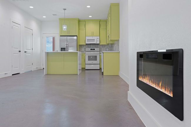 Kitchen with decorative backsplash, light countertops, white appliances, finished concrete floors, and green cabinetry | Image 4