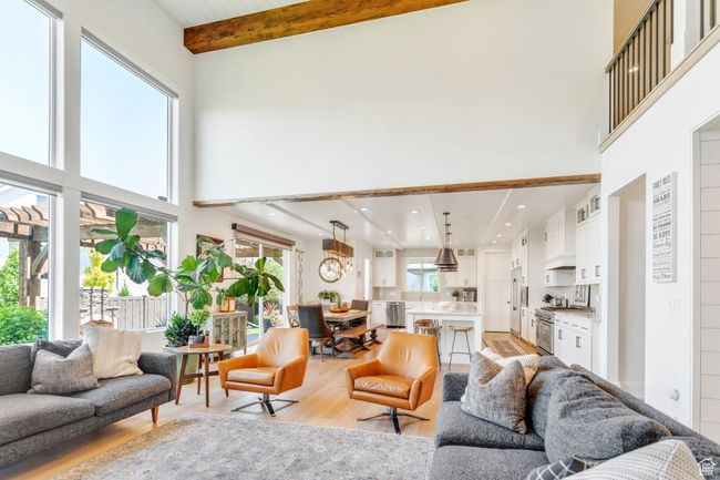 Living area with a high ceiling, light wood-style floors, beam ceiling, and a chandelier | Image 11