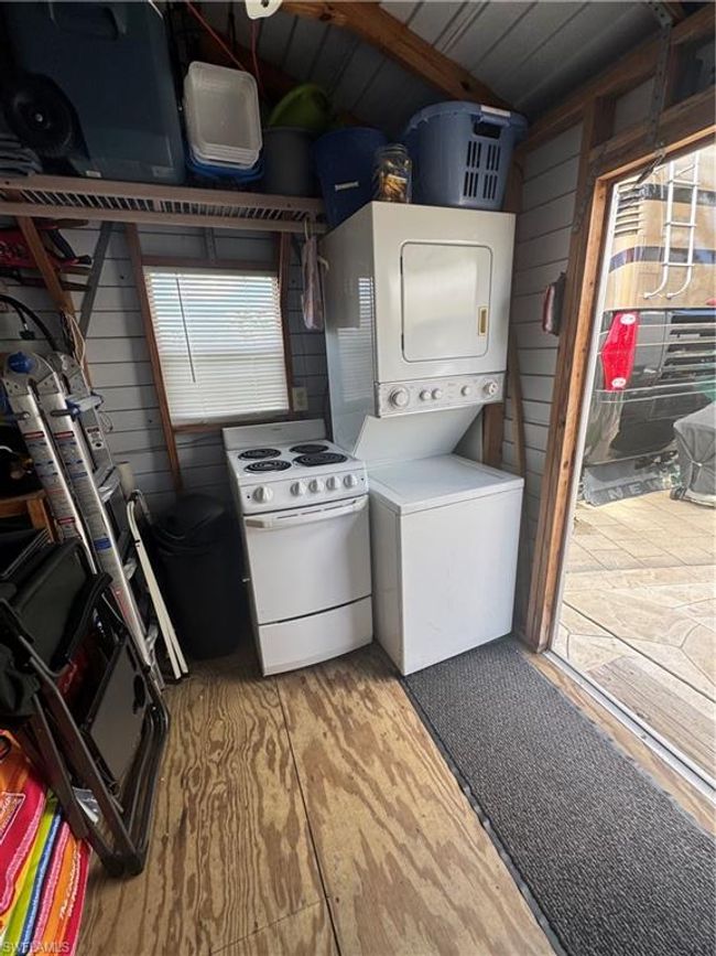 Clothes washing area featuring stacked washing maching and dryer, wood-type flooring, and wood walls | Image 30