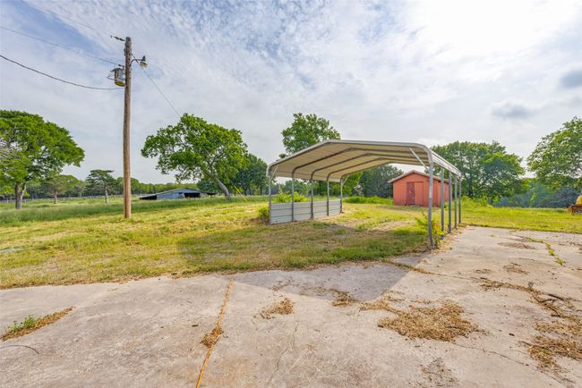 View of yard with a carport, driveway, and an outbuilding | Image 34