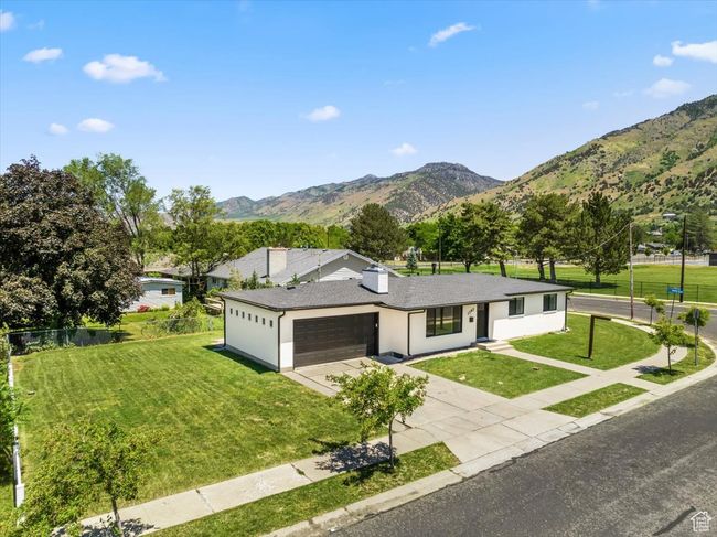 Single story home featuring an attached garage, a mountain view, driveway, a front lawn, and stucco siding | Image 38