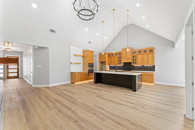 Kitchen featuring open shelves, light countertops, high vaulted ceiling, backsplash, and a center island with sink | Image 6