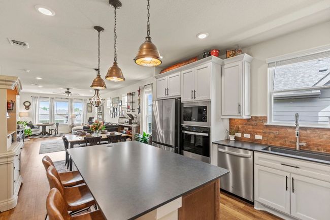 Kitchen featuring stainless steel appliances, dark countertops, visible vents, a sink, and ceiling fan | Image 8