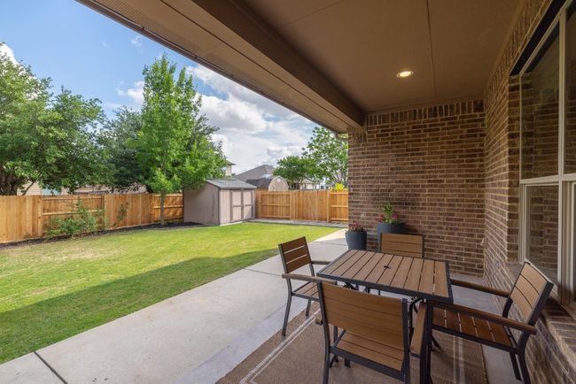 View of patio / terrace with a storage shed, an outdoor structure, a fenced backyard, and outdoor dining space | Image 38