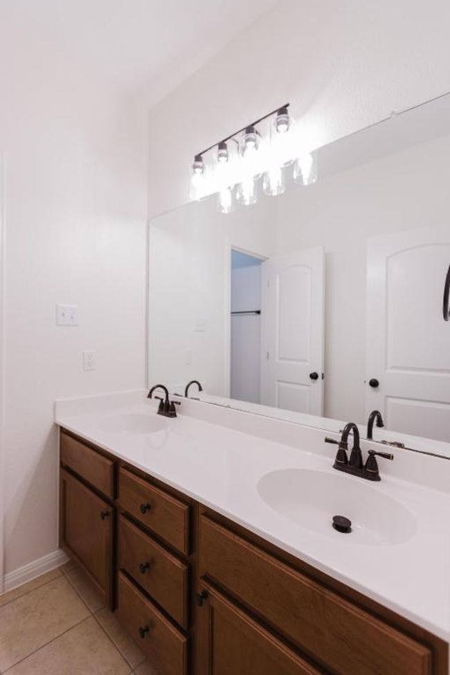 Upstairs Full bathroom with door separating vanity are from bathing area with tile patterned floors, double vanity, and a sink | Image 23