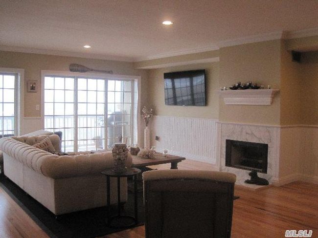 Living area with wainscoting, ornamental molding, wood finished floors, a high end fireplace, and recessed lighting | Image 4